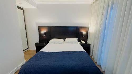 a bedroom with a large bed with a blue blanket at HOTEL PERDIZES - FLAT Executivo - 1208 in Sao Paulo