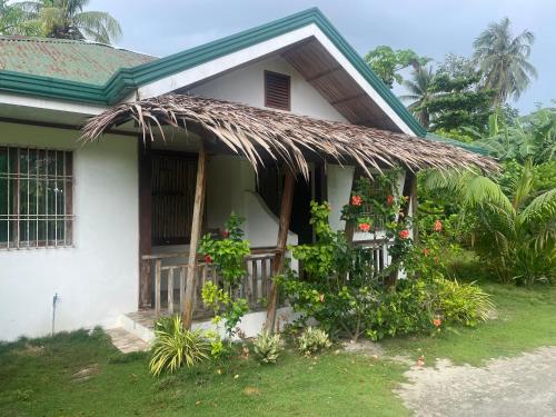 a house with a thatched porch with flowers and plants at Pore's Homestay in General Luna