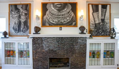 a fireplace in a living room with pictures on the wall at African Oasis Luxury Inn at the Gallery in Mount Vernon