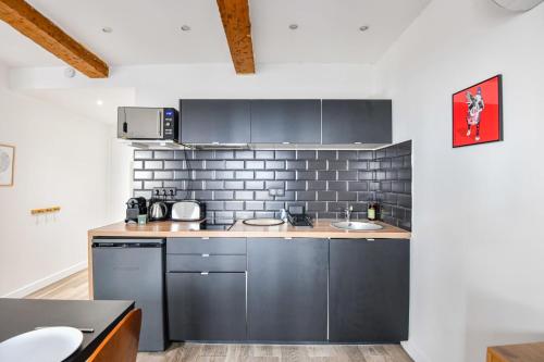 d'une cuisine avec des appareils en acier inoxydable et un mur en briques. dans l'établissement Le Breteuil - Appart standing proche Vieux-Port, à Marseille