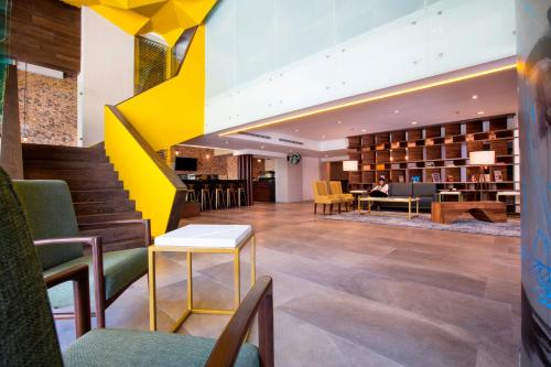 a lobby of a hotel with a yellow staircase at Krystal Urban Guadalajara in Guadalajara