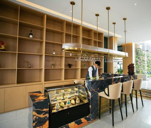 a man standing at a bar in a restaurant at Ramada by Wyndham Vientiane Central in Vientiane