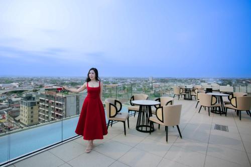 a woman in a red dress standing on a balcony at Ramada by Wyndham Vientiane Central in Vientiane