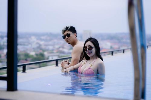 a man and a woman in a swimming pool at Ramada by Wyndham Vientiane Central in Vientiane