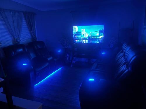 a dark living room with a couch and a tv at LED Lighting Reclining Sofas Cozy 3 Bedroom Home in Jacksonville
