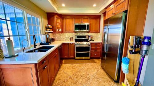 a kitchen with wooden cabinets and a stainless steel refrigerator at Pet-Friendly Beach Home with Fenced Yard in Huntington Beach