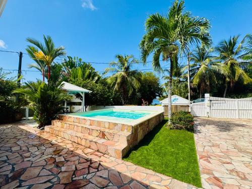 a swimming pool in a yard with a stone wall at Villa Yaya in Le Robert