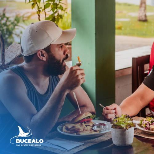 a man sitting at a table eating a sandwich at La Posada del Buzo in Colón