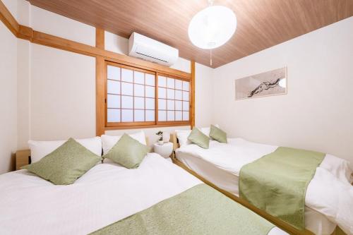 a bedroom with two beds and a window at 真 Private accommodation with sauna, close to USJ and Expo Park, free parking, 4 bedrooms, 8 beds, 2 bathrooms in Osaka