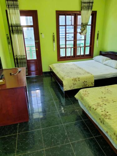 two beds in a room with green walls and windows at MUINE MOMO Homestay in Ấp Khánh Phước (1)