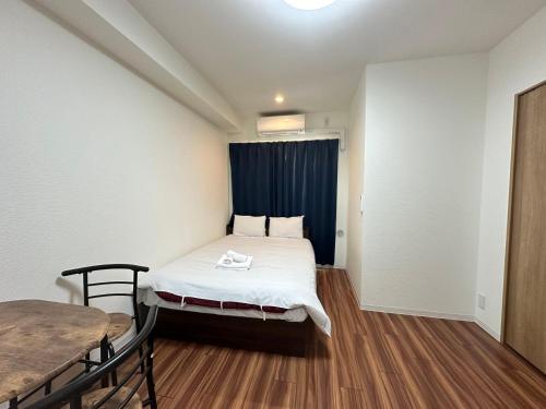ein kleines Zimmer mit einem Bett und einem Tisch in der Unterkunft SOLASIA residence 北上野401 in Tokio