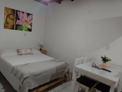 a bedroom with a bed and a table and a painting at Los Colibríes in San José