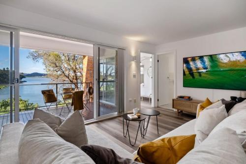 Una sala de estar con un sofá y una ventana grande. en Water-Front Wonder Near Woy Woy, en Blackwall