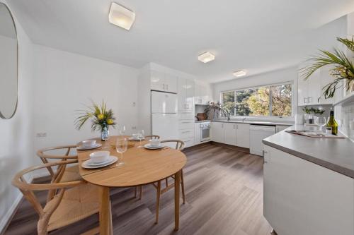 Una cocina y un comedor con mesa y sillas de madera. en Water-Front Wonder Near Woy Woy, en Blackwall
