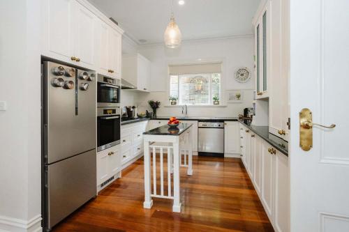 a kitchen with white cabinets and a stainless steel refrigerator at Luxurious Living With Fire Place & Parking in Lower Plenty