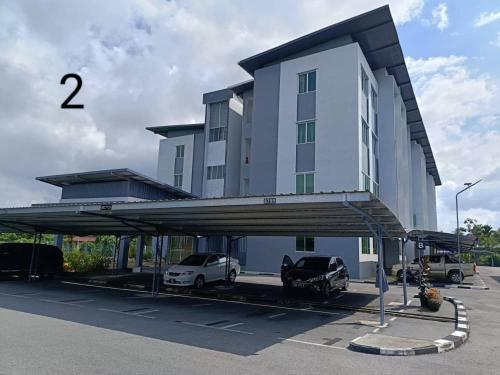 a building with two cars parked in a parking lot at Alan Garden Apartment in Sibu