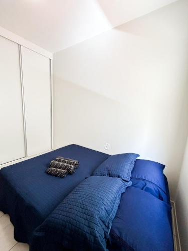 Una cama azul con almohadas en el dormitorio en Apto próximo Ufu, Parque do Sabia, Madrecor, en Uberlândia