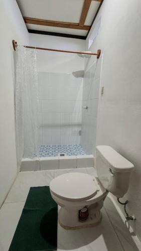 a white bathroom with a toilet and a shower at Mayan Spirit in Flores