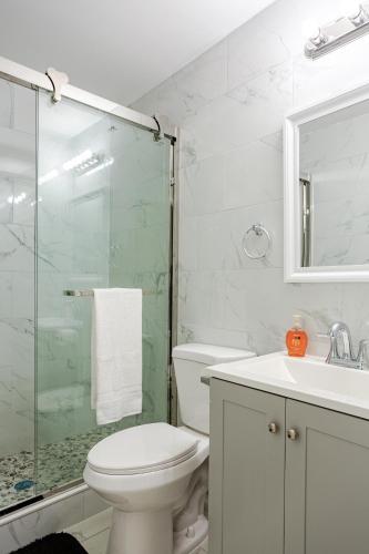 a bathroom with a toilet and a glass shower at Stylish Stay in Center City, French-Japanese & Minimalist Vibes in Philadelphia