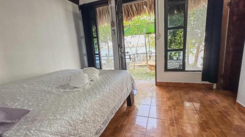 a bedroom with a white bed and large windows at Mayan Spirit in Flores