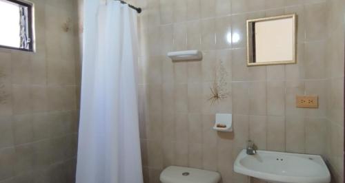 a bathroom with a white shower curtain and a toilet at Hotel Almirante Padilla in Ríohacha