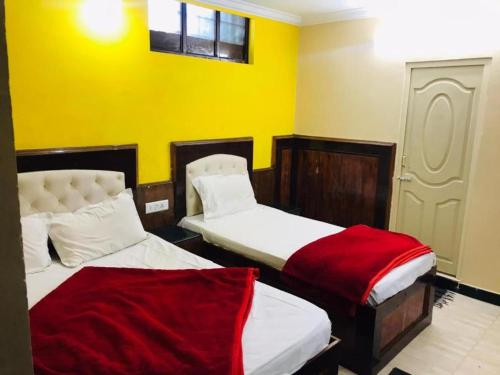 two beds in a room with yellow walls at Hotel mystique inn in Ooty