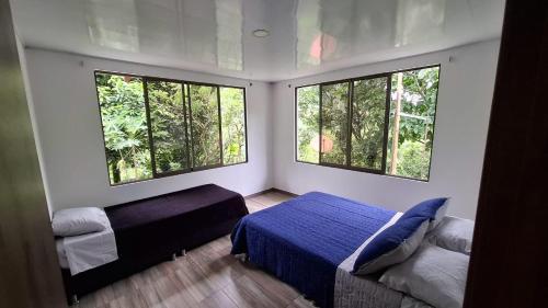 a bedroom with a bed and two windows at Eco Retiro La Paz in Vergara