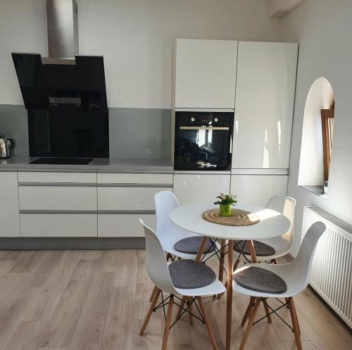 a kitchen with a white table and white chairs at Wielkopolska 22 in Szczecin
