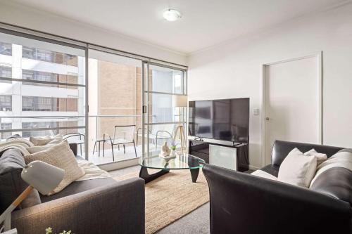 Una sala de estar con un sofá y una mesa de cristal. en Cozy 2BR Apartment Steps from Darling Harbour, en Sídney