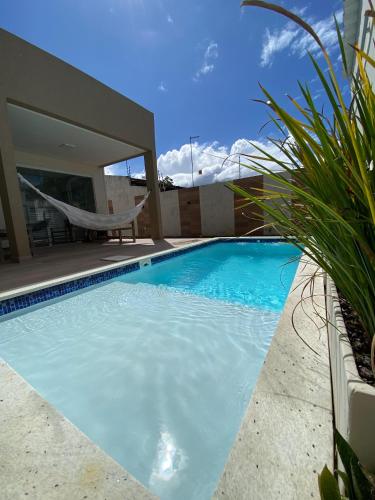 a swimming pool with a hammock and a house at Guaibim House- Sua casa de praia in Guaibim