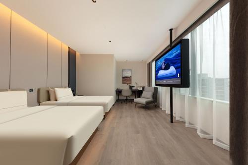 a hotel room with a flat screen tv on a wall at Atour Hotel Hangzhou Cainiao Headquarter Fengxin Road in Hangzhou