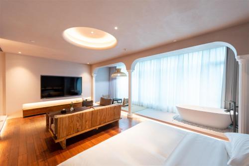a bathroom with a tub and a tv and a large window at Shanheli wabi Sabi Natural Wind Hotel Chenghai Branch in Shantou