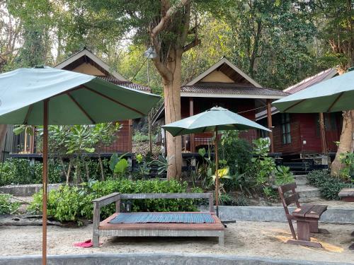 a bench and two umbrellas in front of a house at TipThong Hut in Rayong