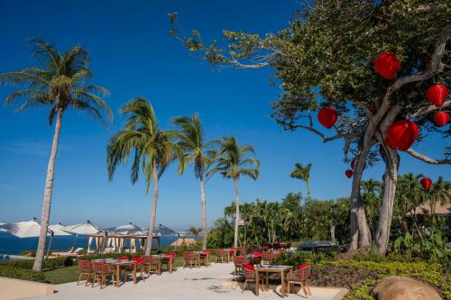 a row of tables and chairs on the beach with palm trees at Banyan Tree Cabo Marques in Acapulco