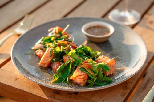 a plate of food with shrimp and greens on a table at Banyan Tree Cabo Marques in Acapulco
