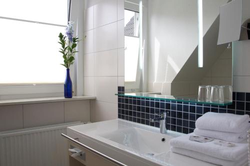 a white bathroom with a sink and a mirror at Mein Inselhotel in Norddorf