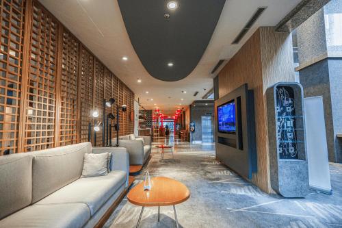 a living room with a couch and a tv at Hotel KIMAYA Slipi Jakarta By HARRIS in Jakarta