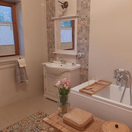 a bathroom with a tub and a sink and a vase of flowers at Villa of Roses in Lanckorona