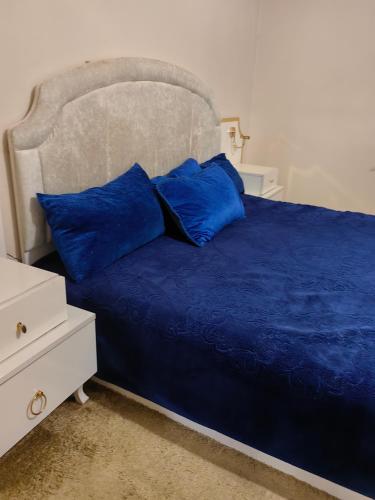 a blue bed with blue pillows and a white dresser at travel adventures 
