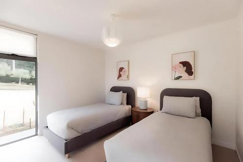 two beds in a white room with a window at Woodbridge Hill Country Escape in Woodbridge
