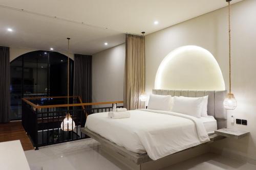 Un dormitorio con una gran cama blanca y un balcón. en Modern loft by Samas Group, en Dalung
