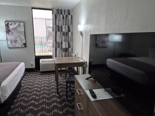 a hotel room with a bed and a desk and a television at Abilene Whitten Inn in Abilene