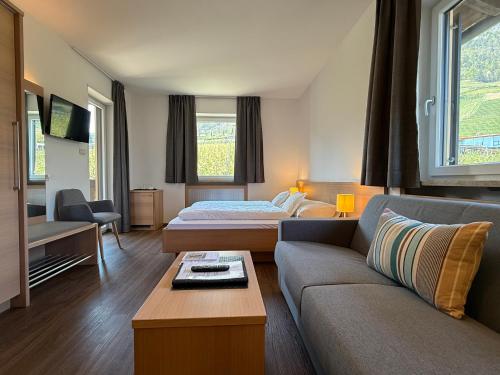 a hotel room with a couch and a bed at Hotel Törggelehof in Cermes