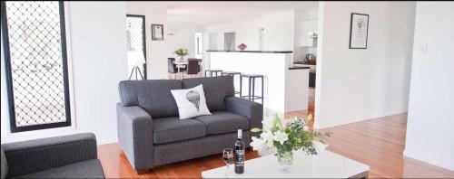a living room with a gray chair and a table at Sanctuary by Sirromet in Mount Cotton