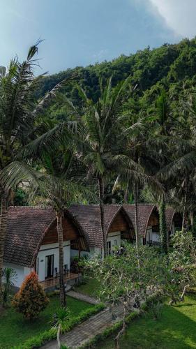 a row of cottages with palm trees at Crystal Bay Villa in Nusa Penida