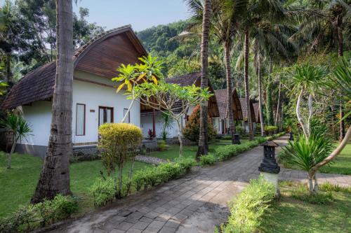 a walkway in front of a house with palm trees at Crystal Bay Villa in Nusa Penida