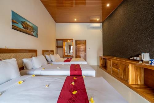 a hotel room with two beds with a red ribbon on them at Kubuku Eco Dive Lodge and Yoga in Pemuteran