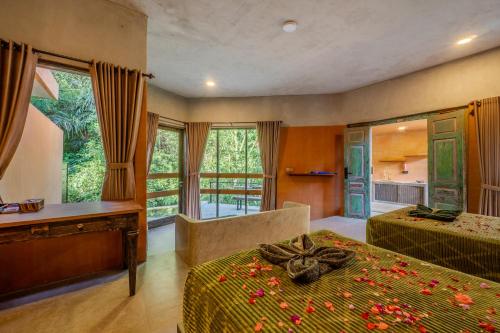 a bedroom with two beds and a desk and windows at Sun Sang Eco Retreats in Tabanan