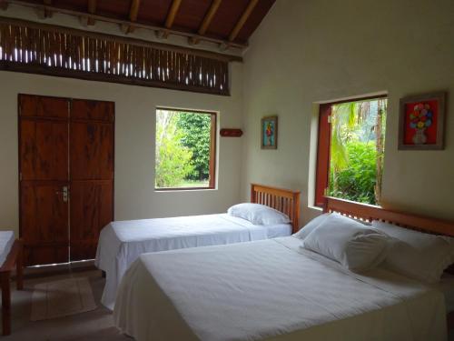 two beds in a room with two windows at Vila do Teteco Ecopousada in Paraty