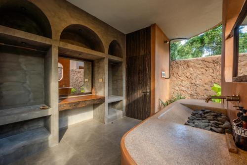a bathroom with a tub and a stone wall at Sun Sang Eco Retreats in Tabanan